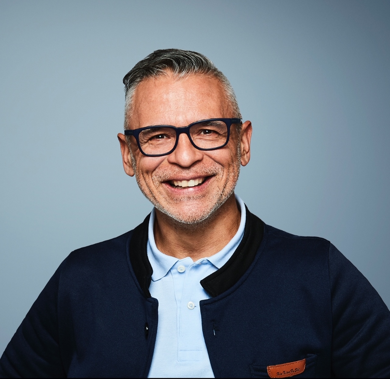 Cesar Marin, smiling headshot in navy jacket and glasses