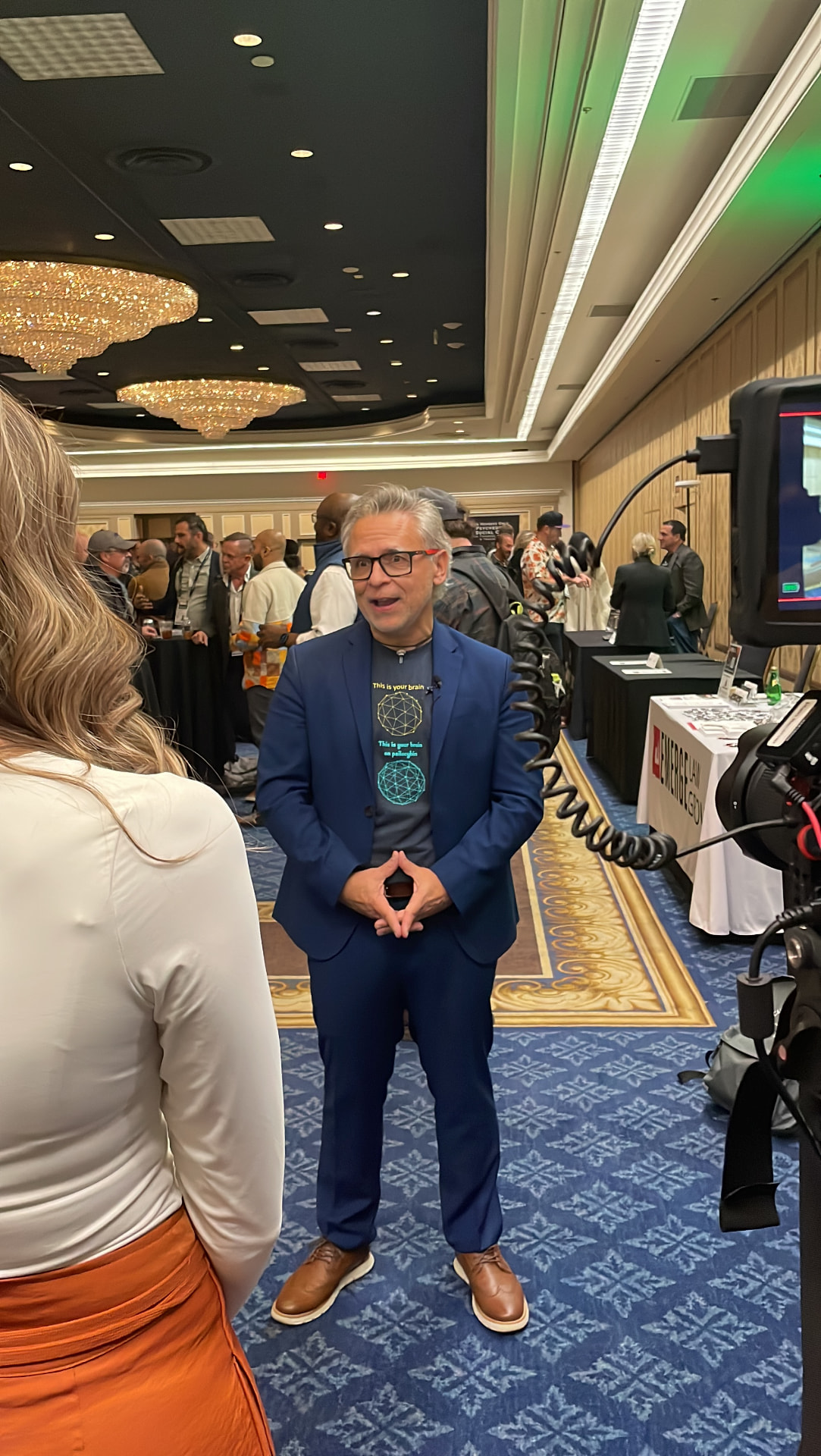 Cesar Marin in a blue suit being interviewed at a conference
